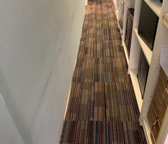 Wet carpet in an office hallway with SERVPRO techs