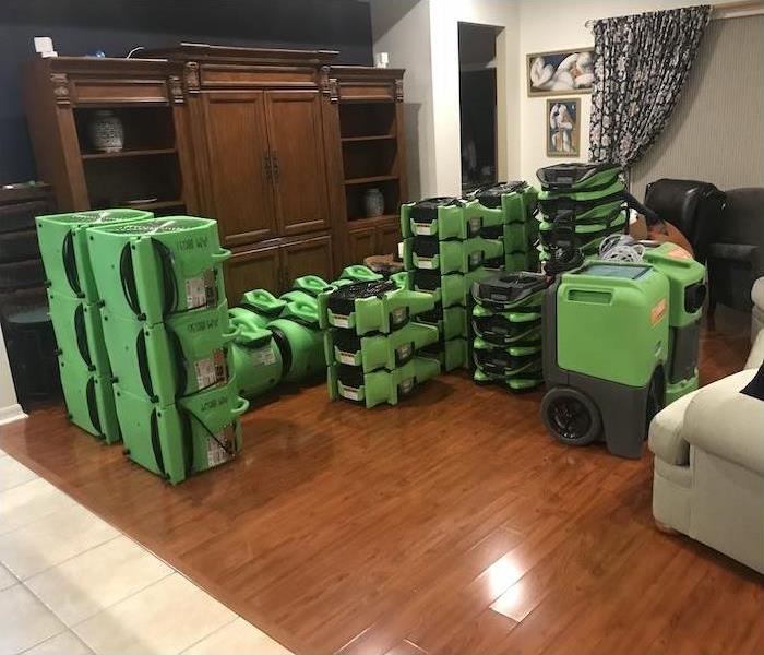 Living room in a home with SERVPRO fans and dehumidifiers stacked on the floor