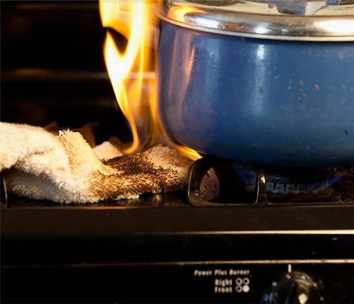 a dish towel ablaze as it is sitting by a stove burner